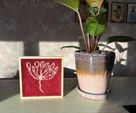 Fleur Getuft schilderij met burgundy achtergrond en licht roze bloem.