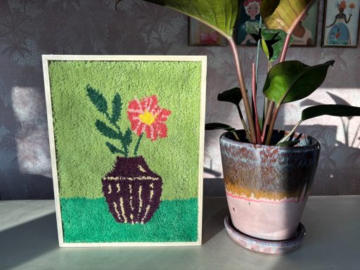 Samantha Tufschilderij met felle kleuren. Groene achtergrond met bloemenvaas.