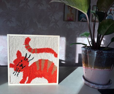 Moos Een handgemaakt tuftwerk van een oranje kat, met een cremekleurige achtergrond.
