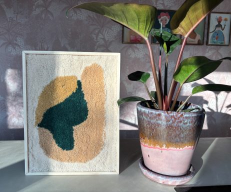 Leonie Tuftschilderij met crème kleurige achtergrond met een taupe kleurige vlek en daar een groene abstracte afbeelding overheen.